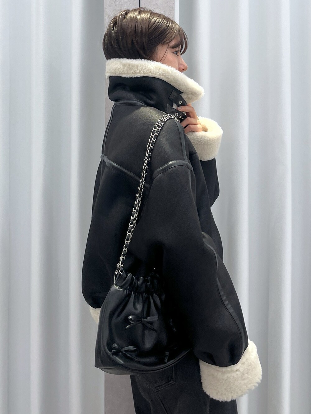 ブラック系のその他アウター、ブルー系のデニムパンツ、オレンジ系のニット/セーターを着用したレディースの冬コーディネートの6枚目の写真