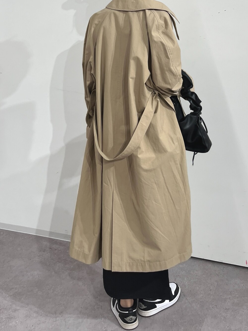ベージュ系のトレンチコート、レッド系のTシャツ/カットソー、ブラック系のスカートを着用したレディースの春コーディネートの3枚目の写真