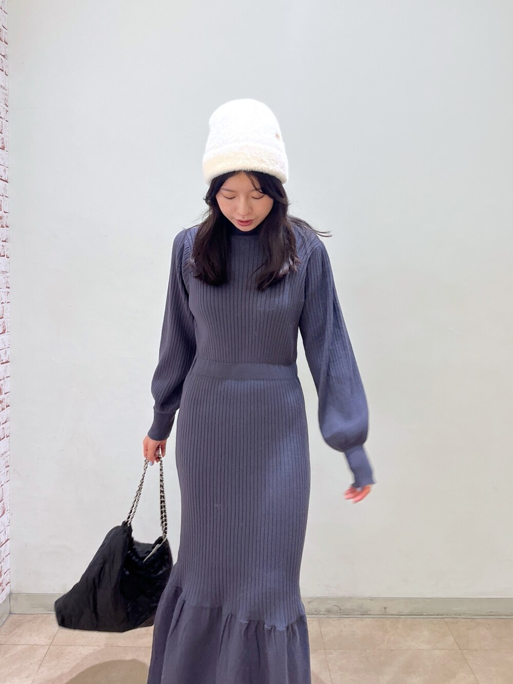 ブラック系のワンピース、ブラック系のブーツ、ブラック系のトートバッグを着用したレディースの冬コーディネートの3枚目の写真