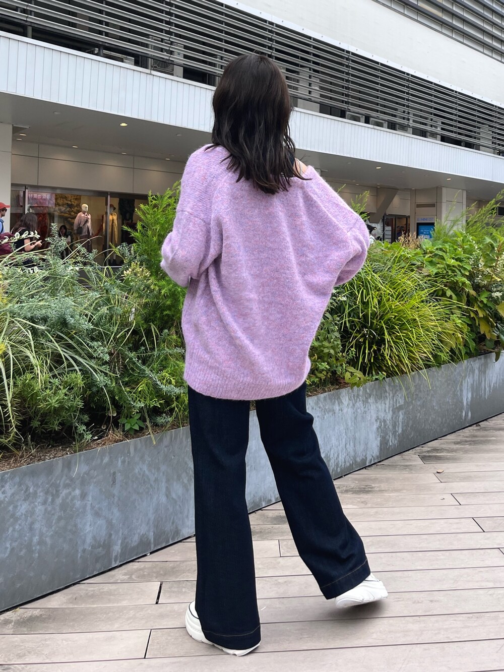 パープル系のカーディガン/ボレロ、ブルー系のデニムパンツ、ブラック系のスニーカーを着用したレディースの秋コーディネートの3枚目の写真