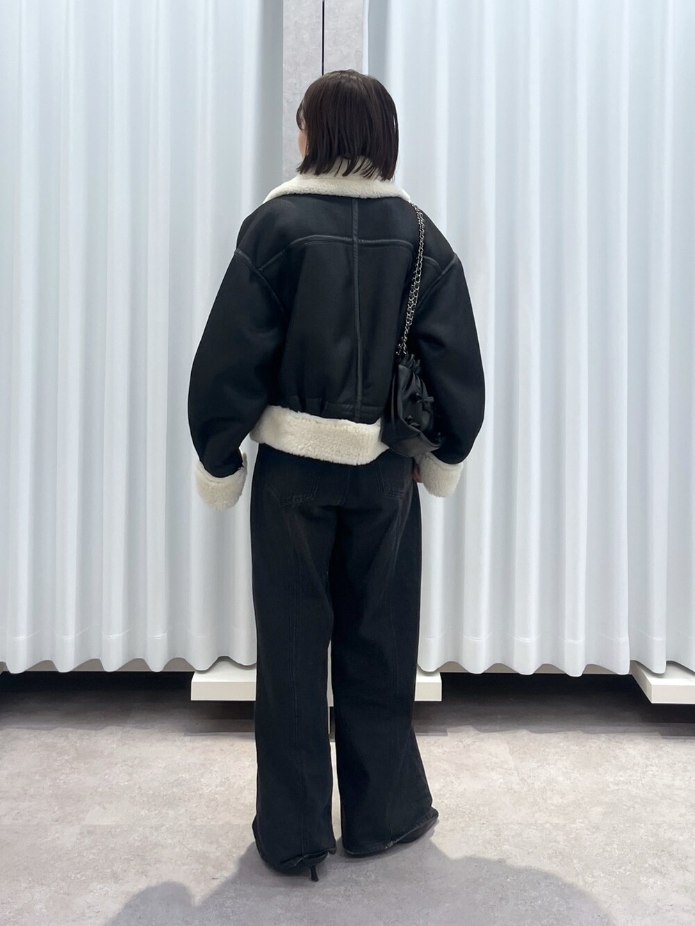 ブラック系のその他アウター、ブルー系のデニムパンツ、オレンジ系のニット/セーターを着用したレディースの冬コーディネートの3枚目の写真