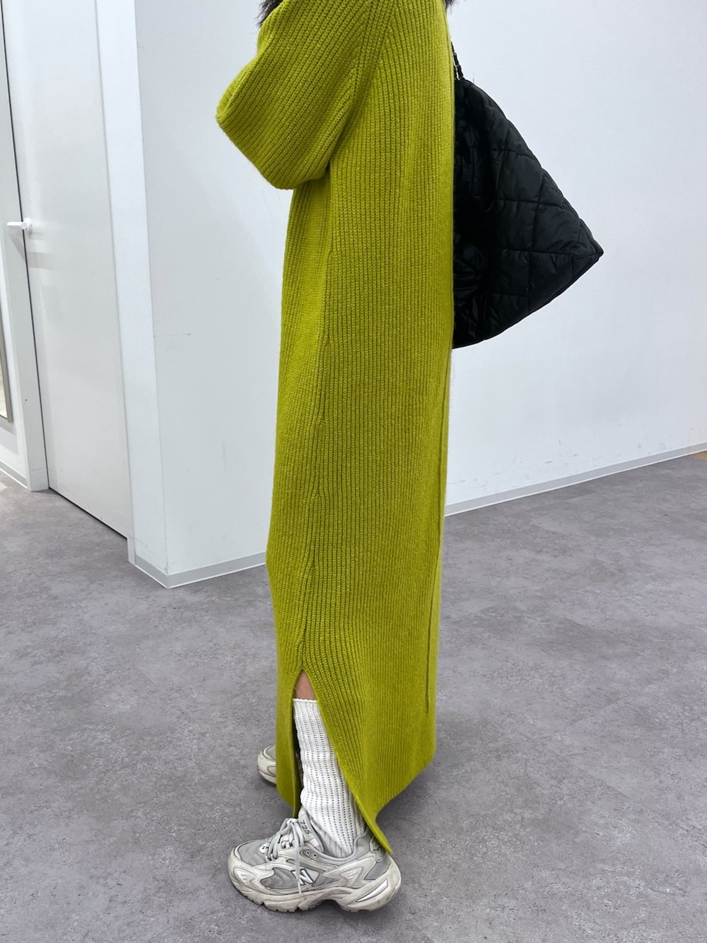 グリーン系のワンピース、ホワイト系のスニーカーを着用したレディースの冬コーディネートの3枚目の写真