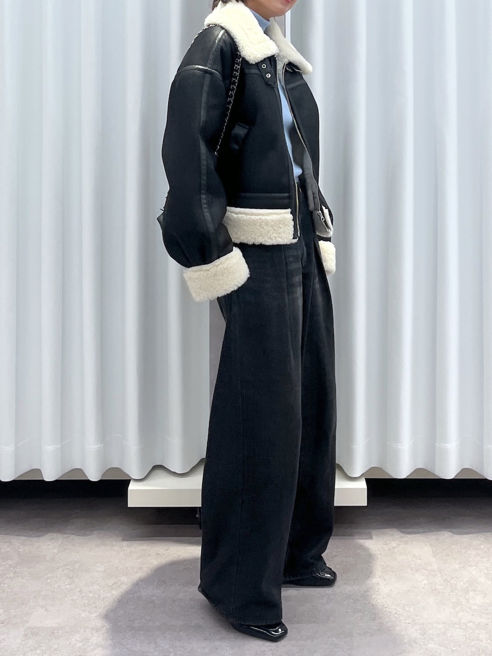 ブラック系のその他アウター、ブルー系のデニムパンツ、オレンジ系のニット/セーターを着用したレディースの冬コーディネートの2枚目の写真