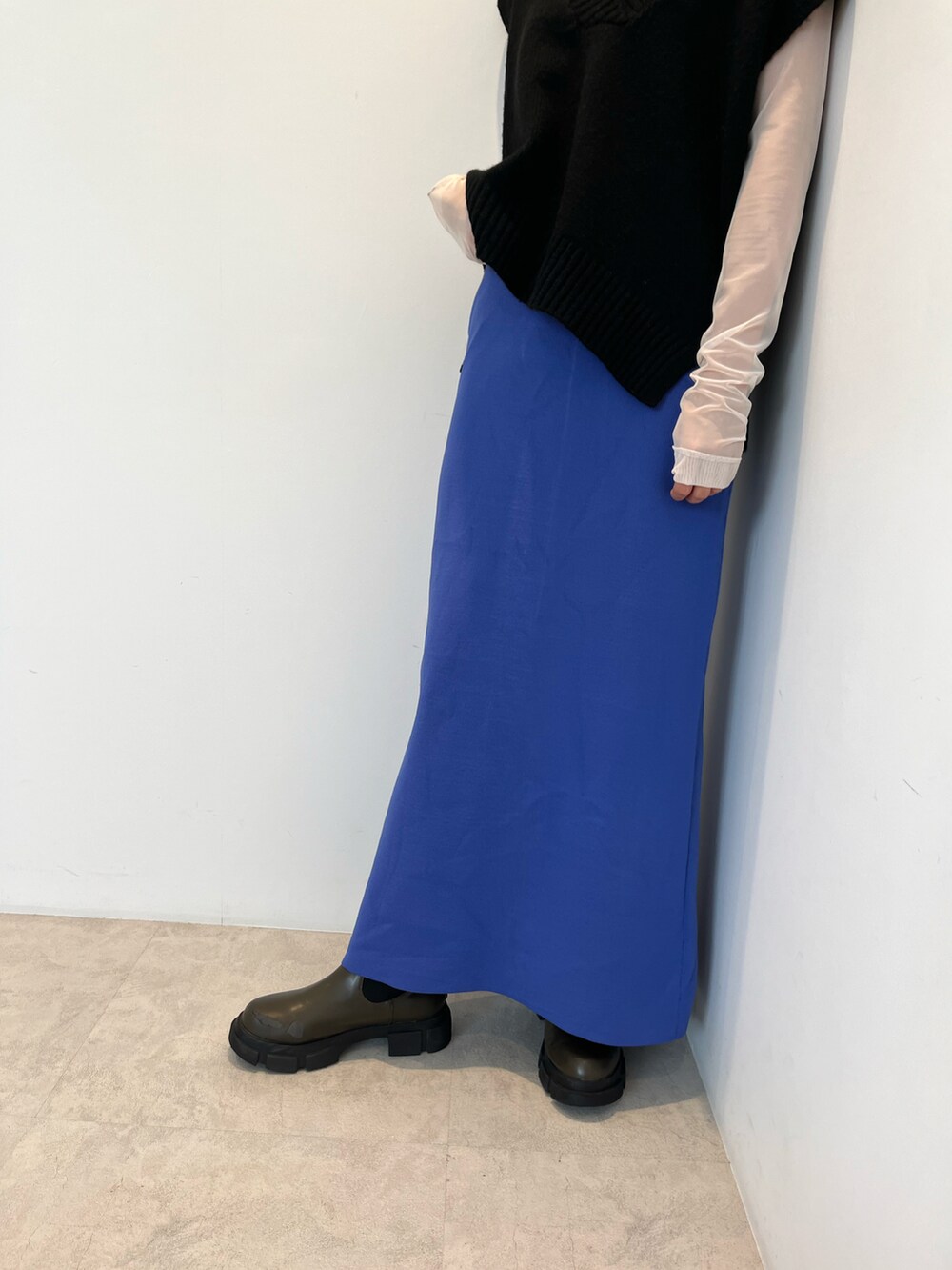 ホワイト系のTシャツ/カットソー、ブラック系のニット/セーター、ブルー系のスカートを着用したレディースの秋コーディネートの4枚目の写真