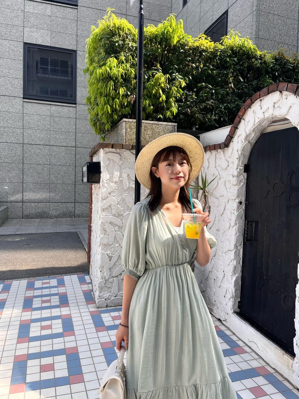 グリーン系のワンピース、ゴールド系のサンダル、ベージュ系のハットを着用したレディースの夏コーディネートの3枚目の写真