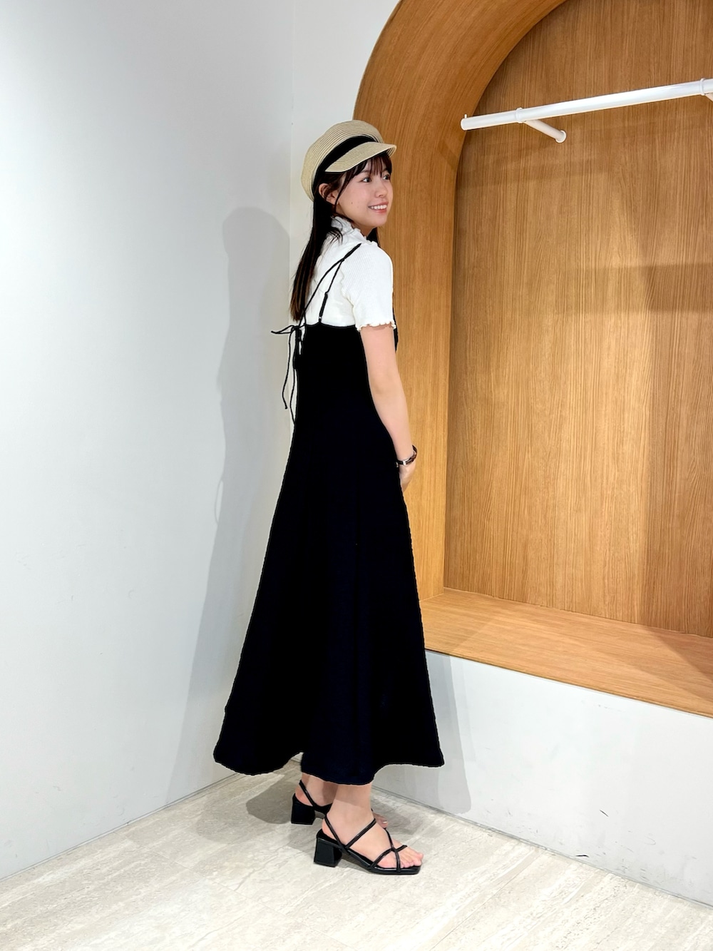 ブラック系のワンピース、ホワイト系のTシャツ/カットソー、ブラック系のサンダルを着用したレディースの春コーディネートの2枚目の写真