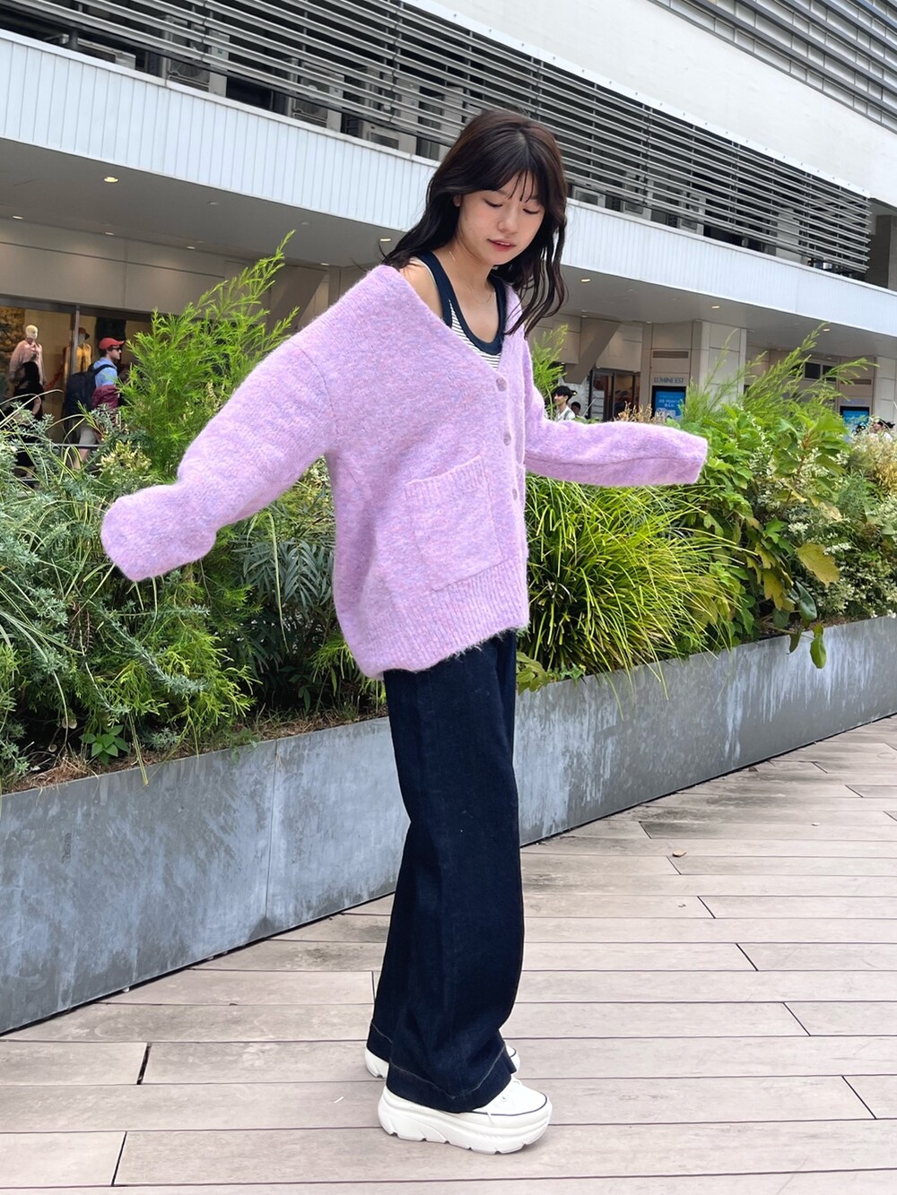 パープル系のカーディガン/ボレロ、ブルー系のデニムパンツ、ブラック系のスニーカーを着用したレディースの秋コーディネートの2枚目の写真