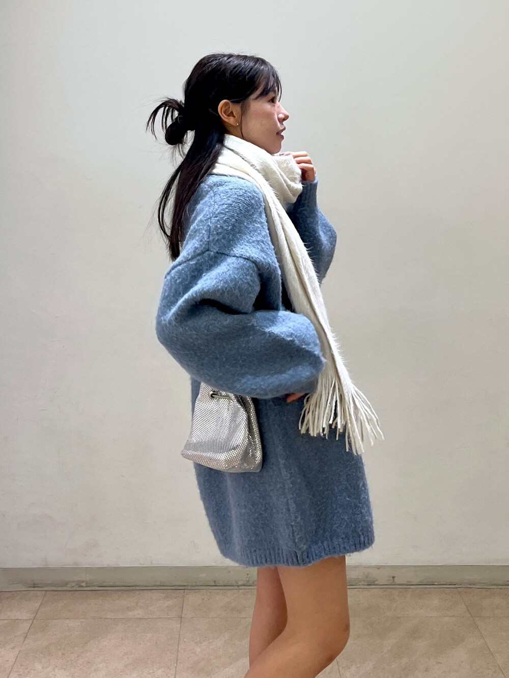 ブルー系のワンピース、シルバー系のハンドバッグ、ブラック系のブーツを着用したレディースの冬コーディネートの4枚目の写真