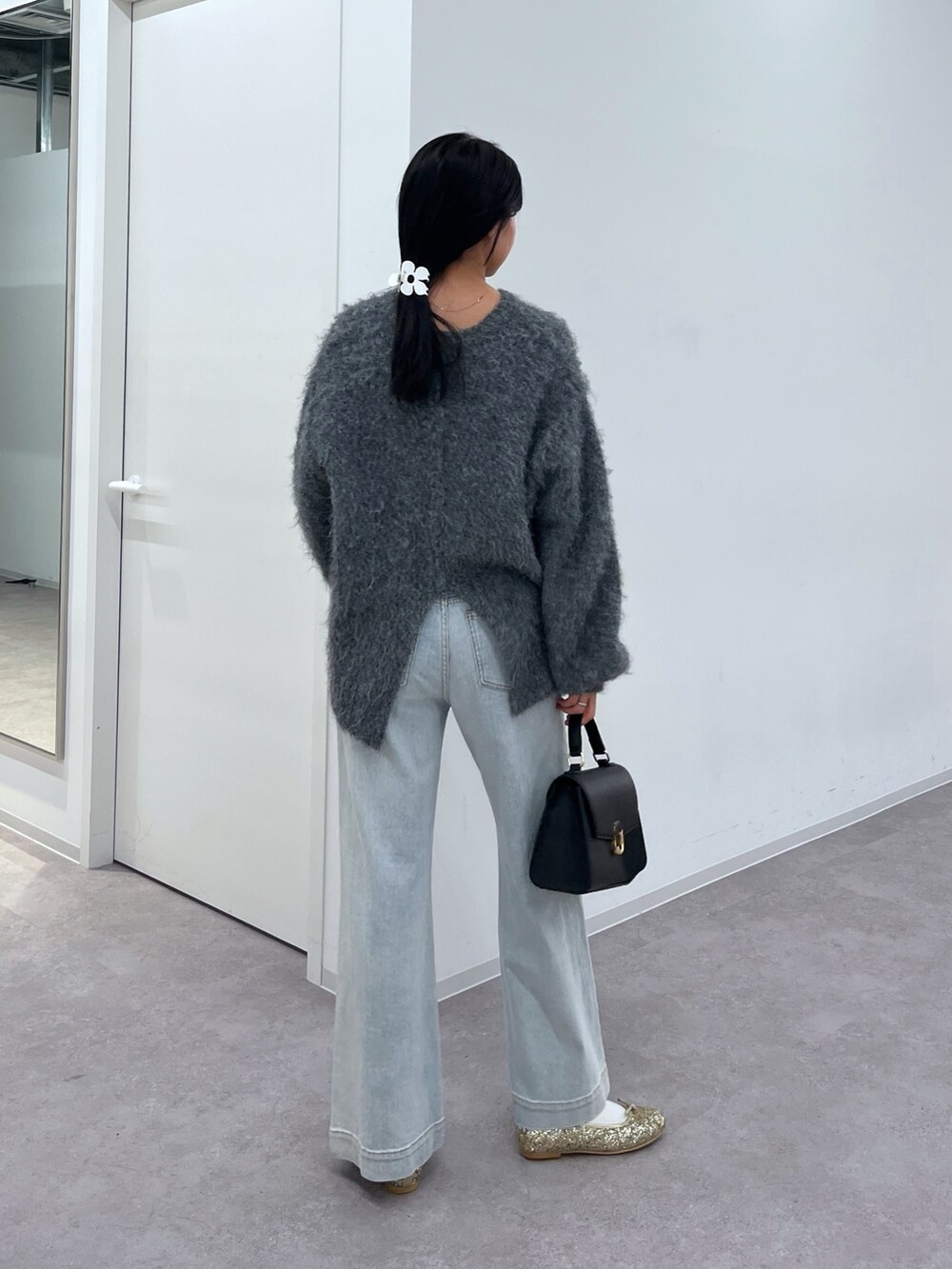 グレー系のニット/セーター、ブルー系のデニムパンツ、ブラック系のショルダーバッグを着用したレディースの冬コーディネートの3枚目の写真