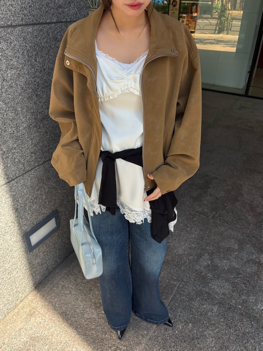 ベージュ系のブルゾン、ホワイト系のワンピース、ブルー系のデニムパンツを着用したレディースの春コーディネートの2枚目の写真