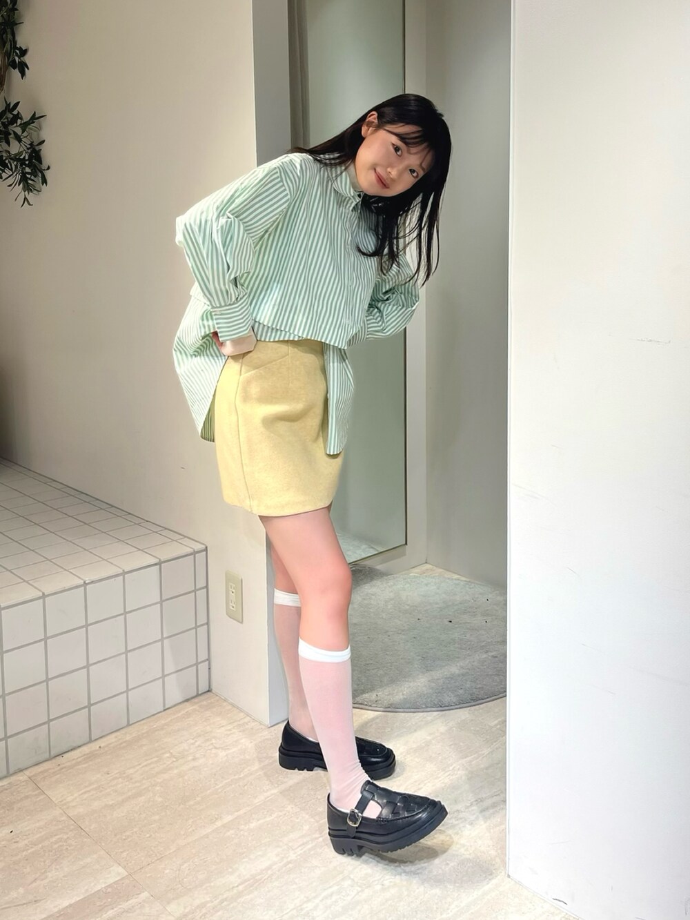 グリーン系のシャツ/ブラウス、イエロー系のスカート、ホワイト系のTシャツ/カットソーを着用したレディースの冬コーディネートの2枚目の写真