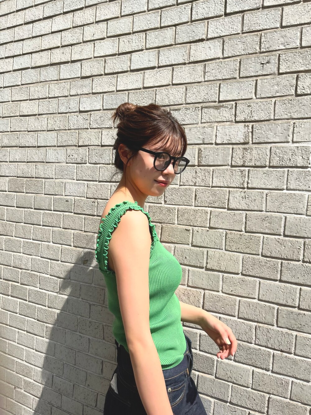 ブラック系のニット/セーター、ホワイト系のデニムパンツ、ブラウン系のショルダーバッグを着用したレディースの夏コーディネートの2枚目の写真