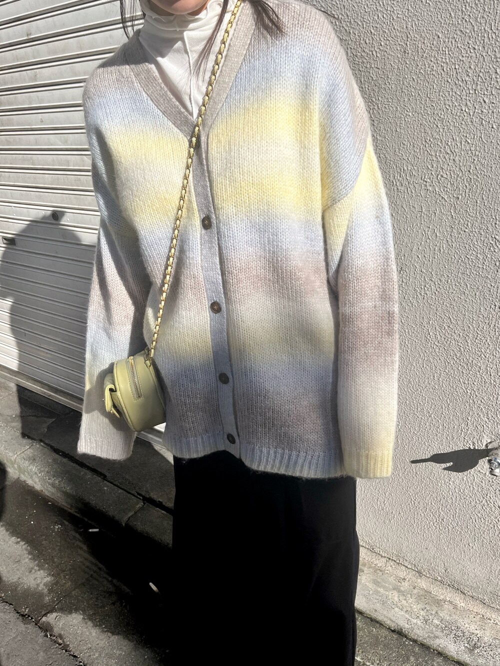 イエロー系のカーディガン/ボレロ、ブラック系のスカート、ベージュ系のブーツを着用したレディースの冬コーディネートの3枚目の写真