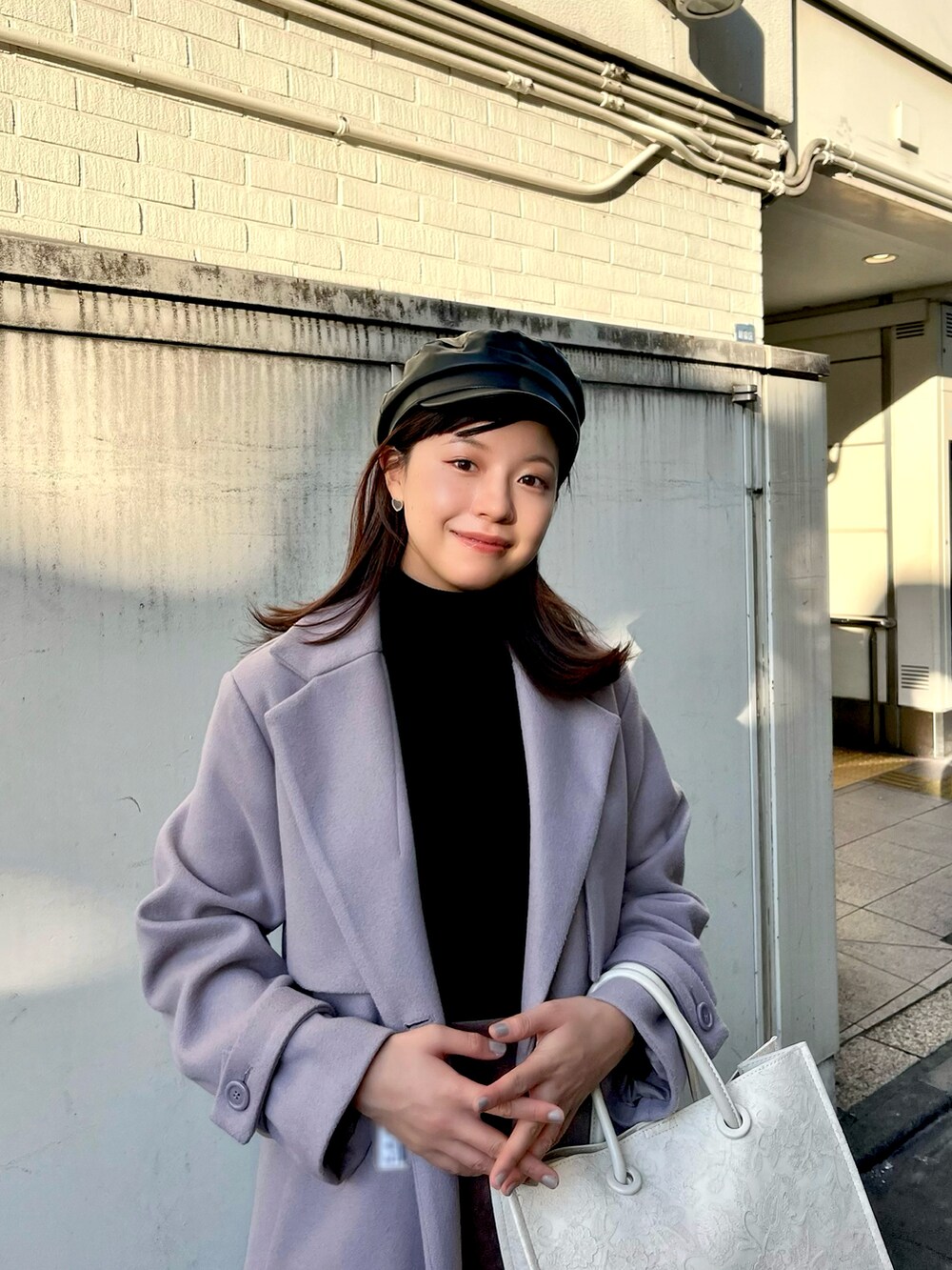 ブラック系のニット/セーター、パープル系のチェスターコート、ブラウン系のスカートを着用したレディースの秋コーディネートの2枚目の写真