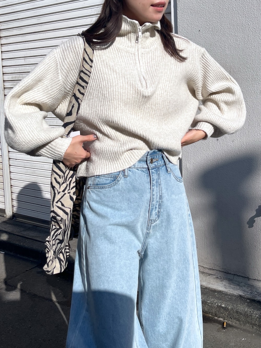 ホワイト系のワンピース、ブルー系のデニムパンツ、ベージュ系のトートバッグを着用したレディースの秋コーディネートの3枚目の写真