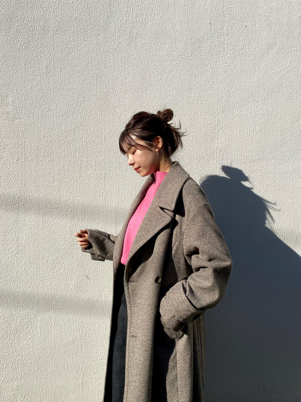 ブラウン系のチェスターコート、ピンク系のニット/セーター、ブラック系のスカートを着用したレディースの冬コーディネートの3枚目の写真