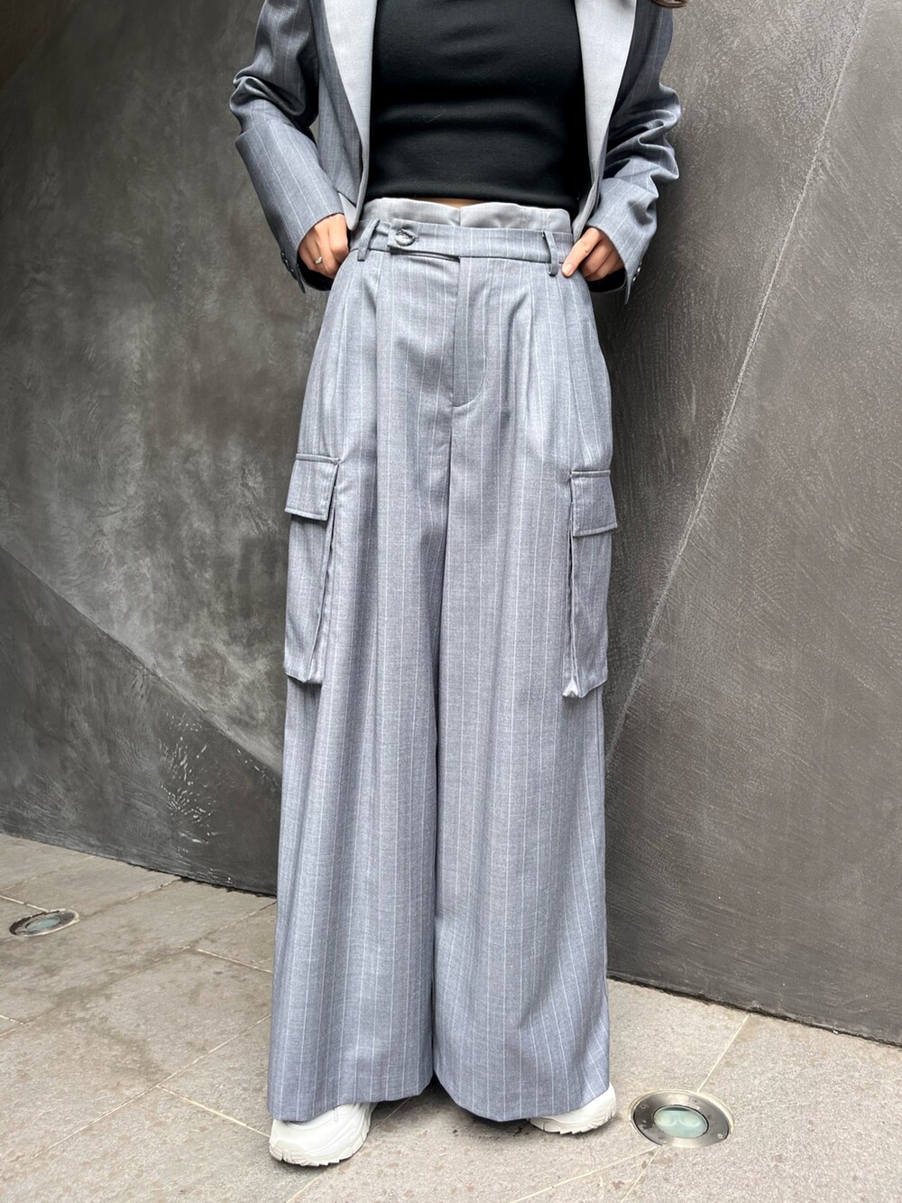 グレー系のテーラードジャケット、グレー系のスラックス、ホワイト系のスニーカーを着用したレディースの秋コーディネートの3枚目の写真