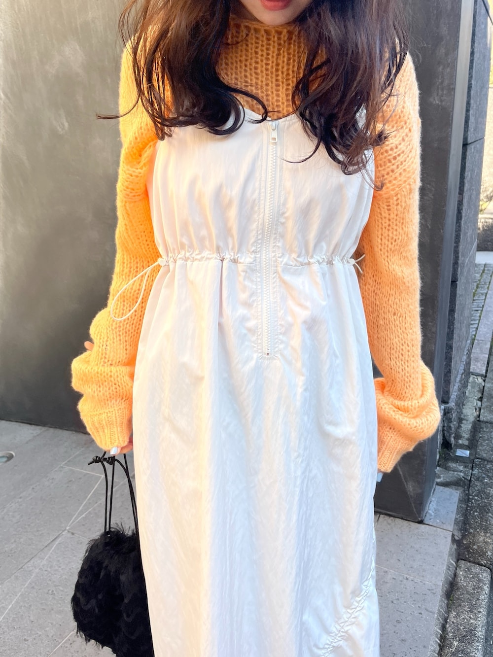 オレンジ系のニット/セーター、ホワイト系のワンピースを着用したレディースの春コーディネートの4枚目の写真