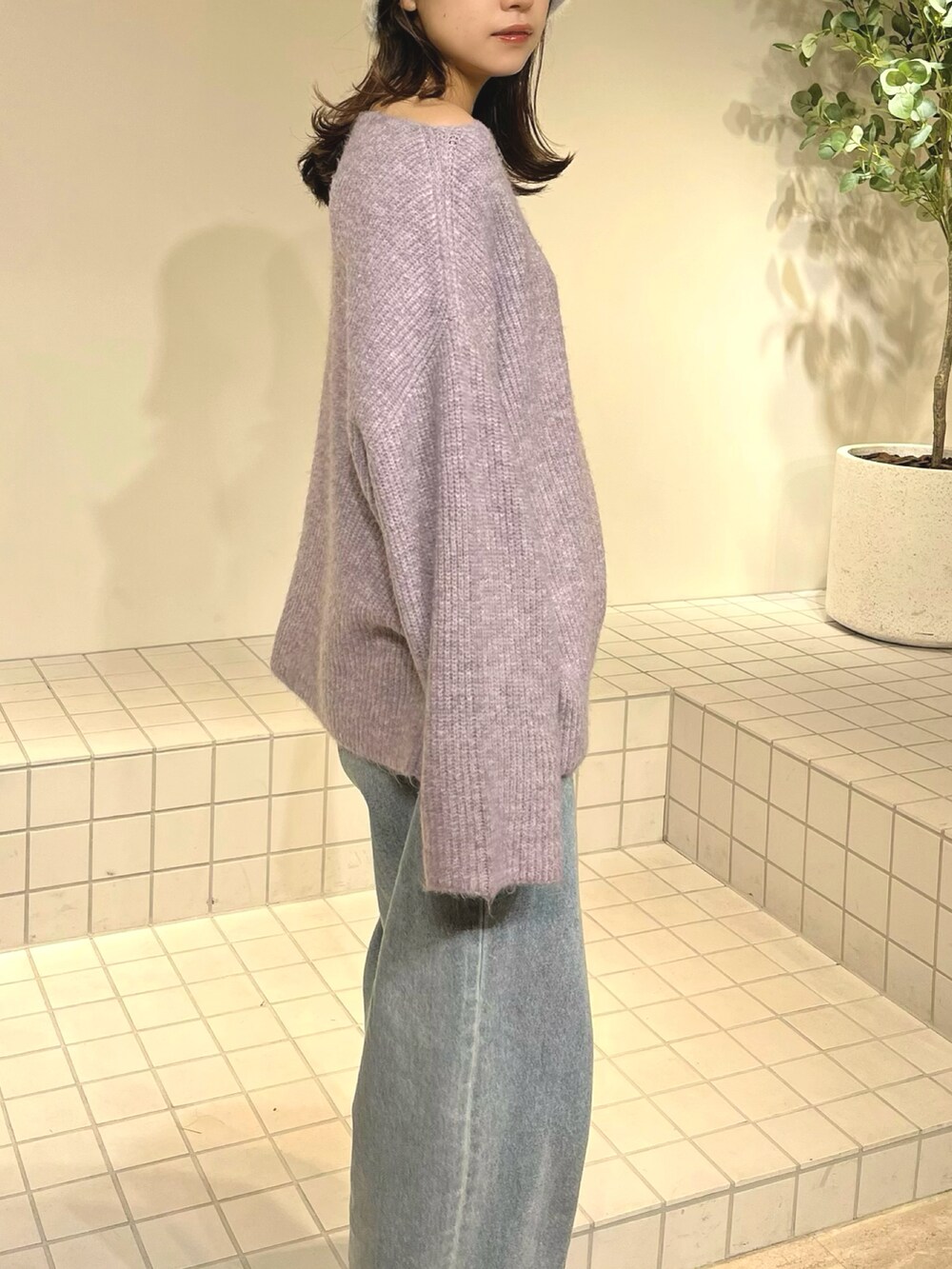 パープル系のニット/セーター、ブルー系のデニムパンツを着用したレディースの冬コーディネートの3枚目の写真