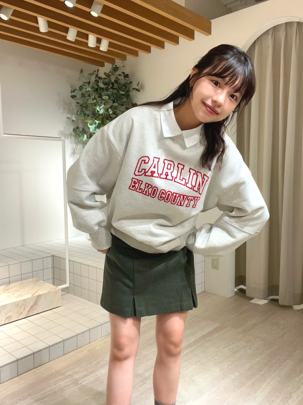 ホワイト系のスウェット、グリーン系のスカート、ブラック系のローファーを着用したレディースの秋コーディネートの2枚目の写真