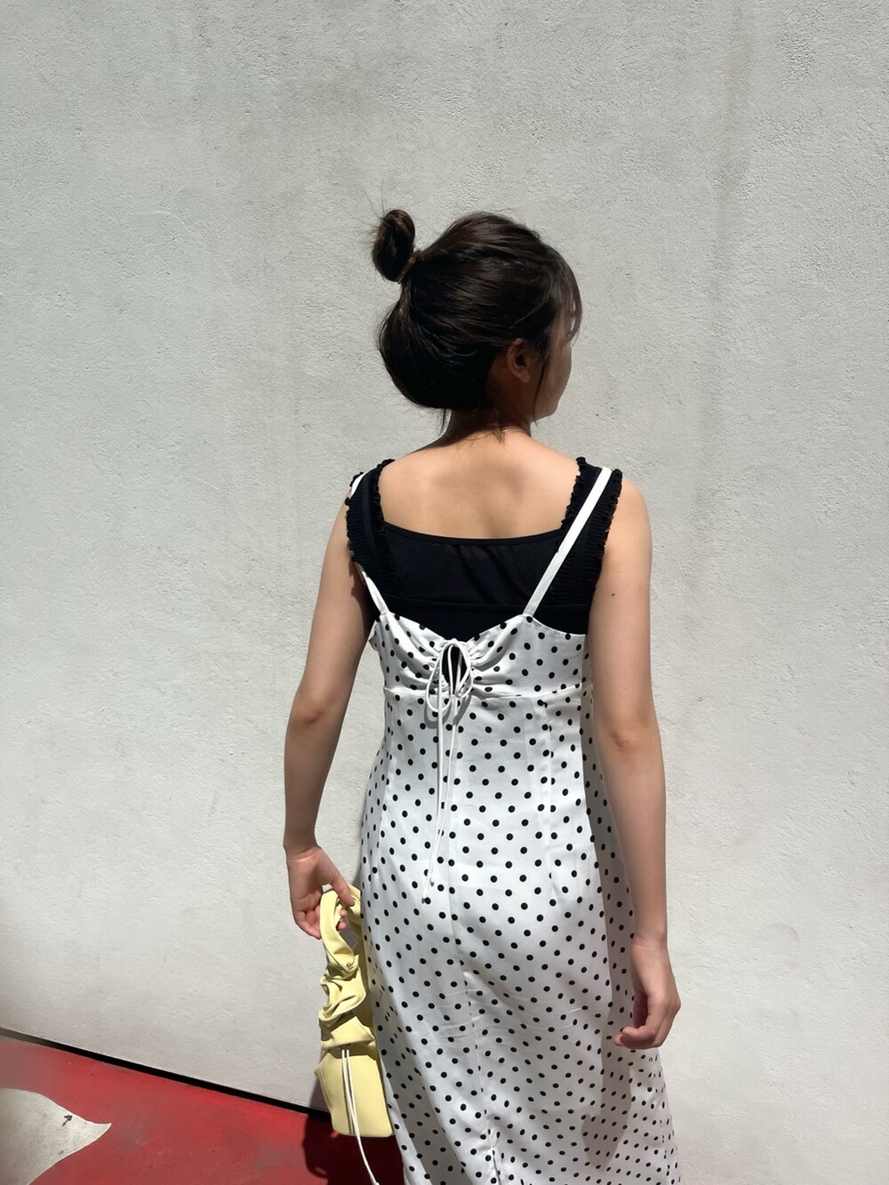 ホワイト系のワンピース、ブラック系のニット/セーター、イエロー系のトートバッグを着用したレディースの夏コーディネートの3枚目の写真