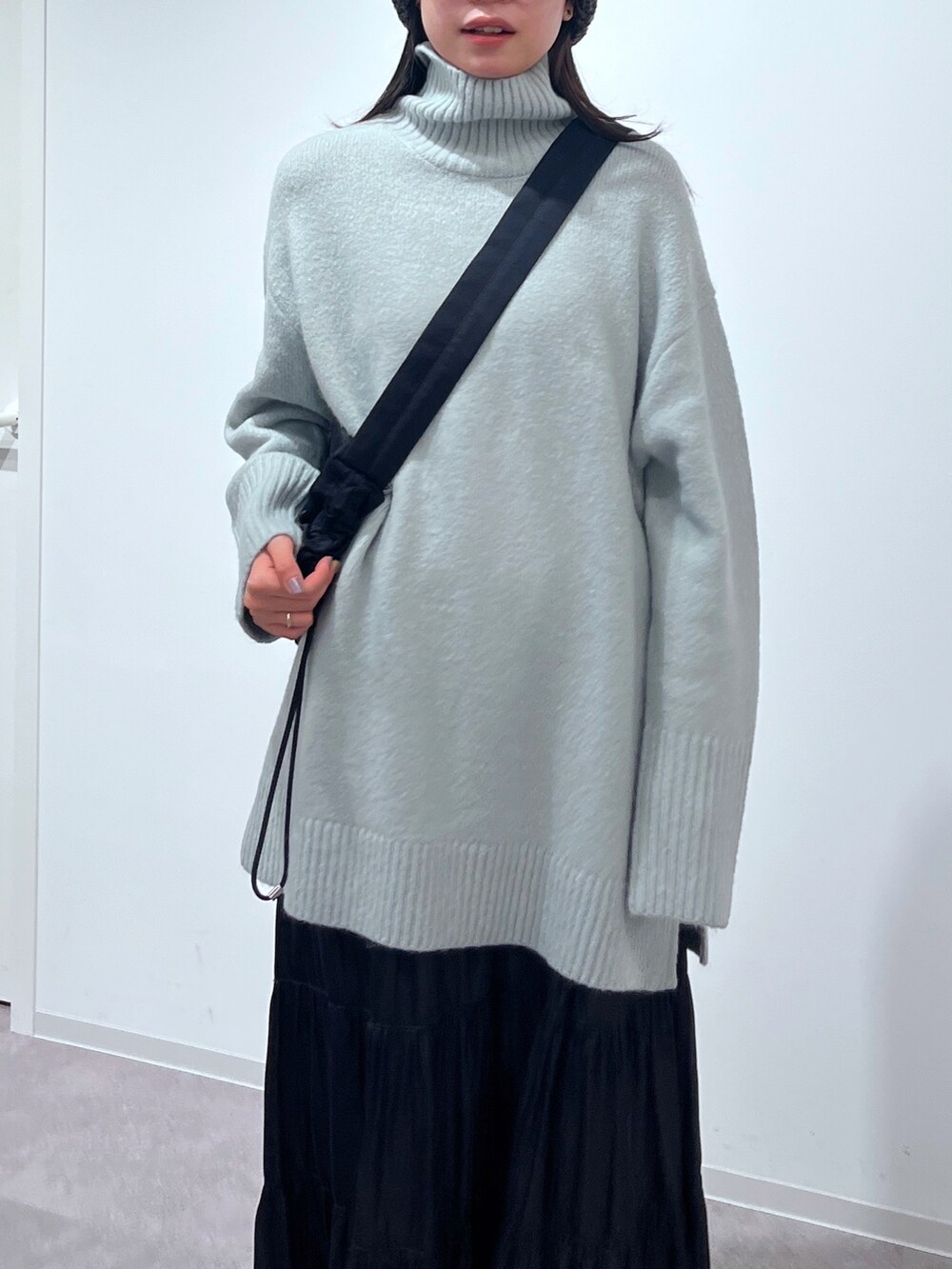 グリーン系のニット/セーター、ブラック系のスカート、ホワイト系のスニーカーを着用したレディースの冬コーディネートの4枚目の写真