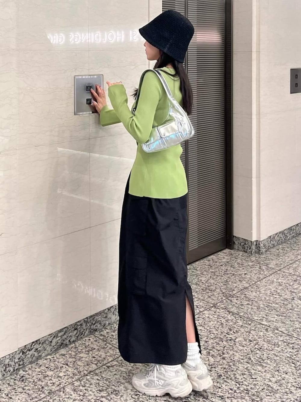 グリーン系のカーディガン/ボレロ、ブラック系のスカート、ホワイト系のスニーカーを着用したレディースの冬コーディネートの2枚目の写真