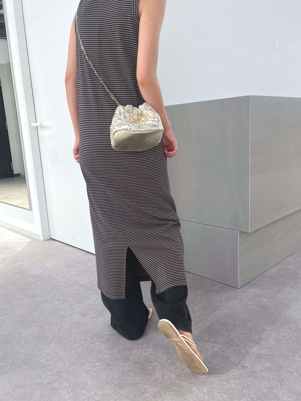 ブラック系のワンピース、ブラック系のデニムパンツ、ホワイト系のサンダルを着用したレディースの夏コーディネートの4枚目の写真