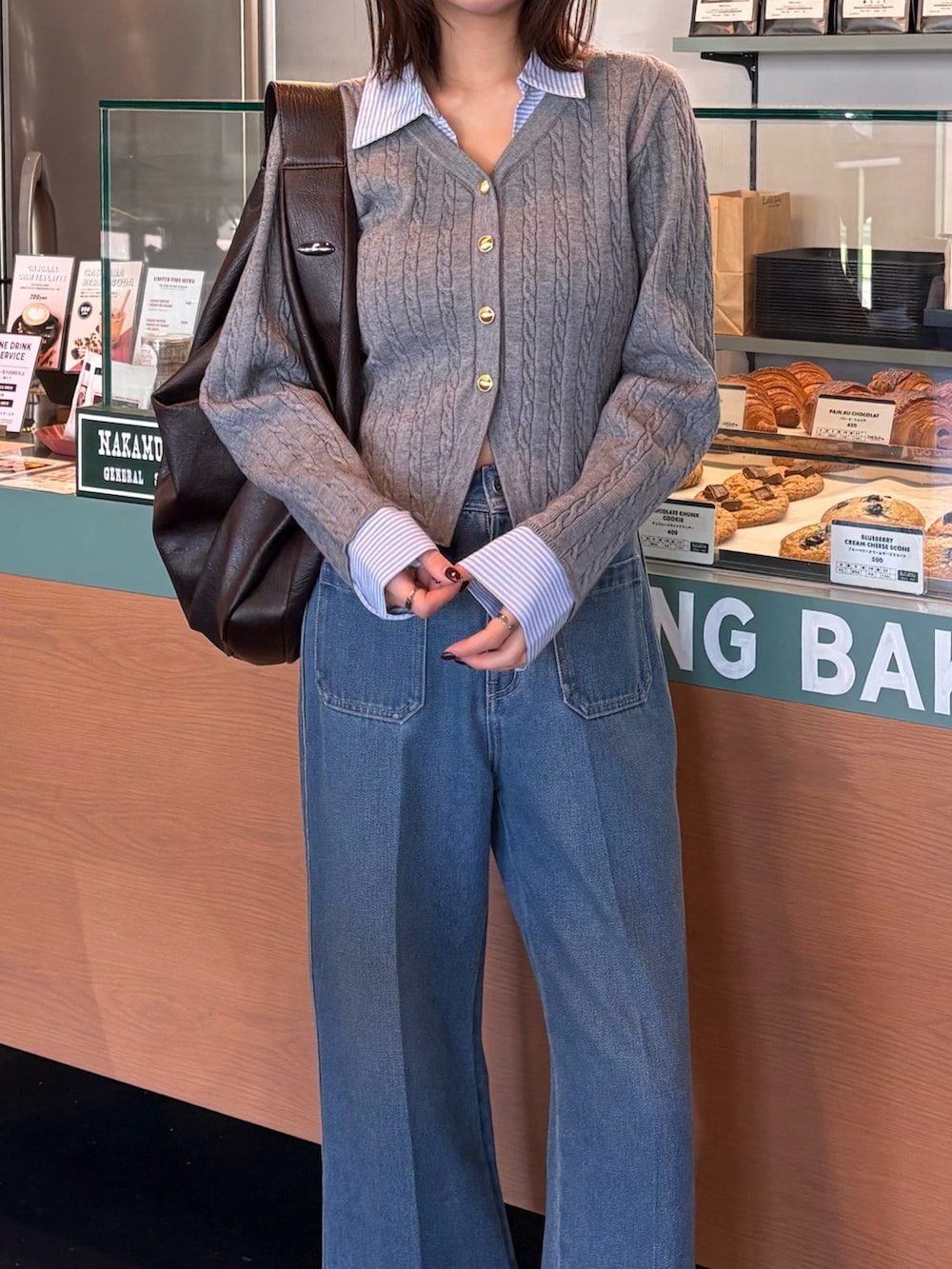 グレー系のニット/セーター、ブルー系のデニムパンツを着用したレディースの冬コーディネートの2枚目の写真