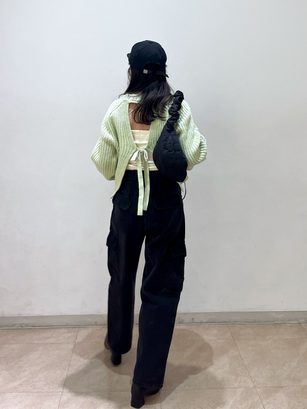 グリーン系のニット/セーター、ブラック系のデニムパンツ、ブラック系のキャップを着用したレディースの冬コーディネートの3枚目の写真