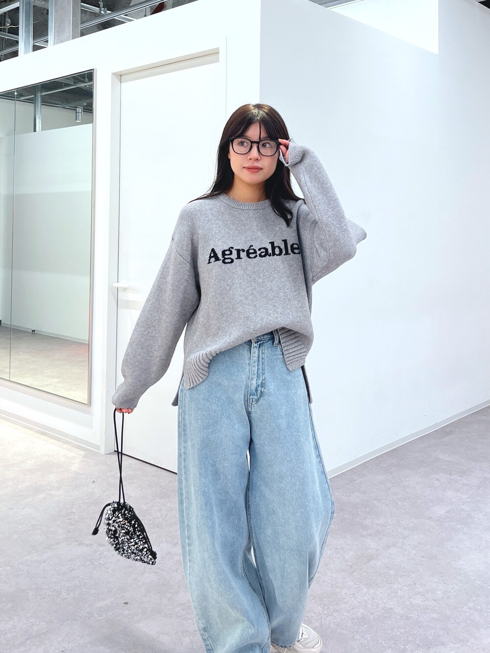 グレー系のニット/セーター、ブルー系のデニムパンツ、ホワイト系のスニーカーを着用したレディースの冬コーディネートの2枚目の写真
