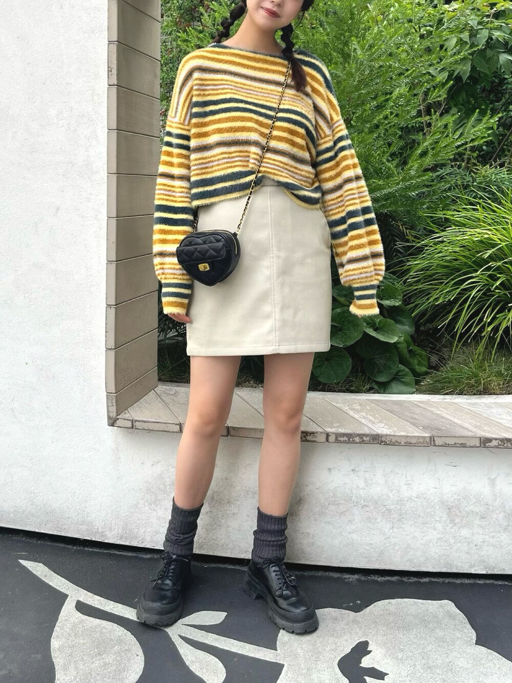 イエロー系のニット/セーター、ホワイト系のスカート、ブラック系のショルダーバッグを着用したレディースの秋コーディネートの3枚目の写真