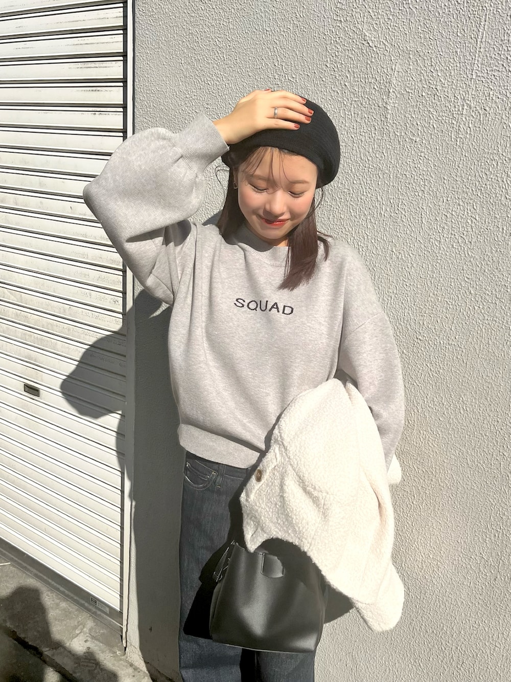 ホワイト系のノーカラージャケット、グレー系のニット/セーター、ブルー系のデニムパンツを着用したレディースの秋コーディネートの3枚目の写真