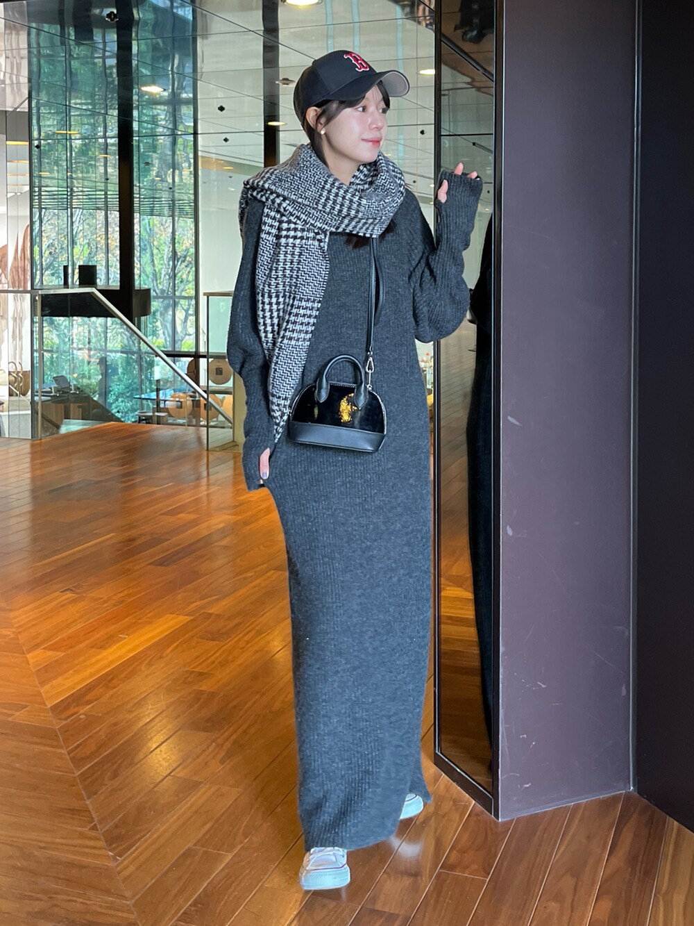 ブラック系のワンピース、オレンジ系のショルダーバッグ、ブラック系のマフラーを着用したレディースの冬コーディネートの2枚目の写真