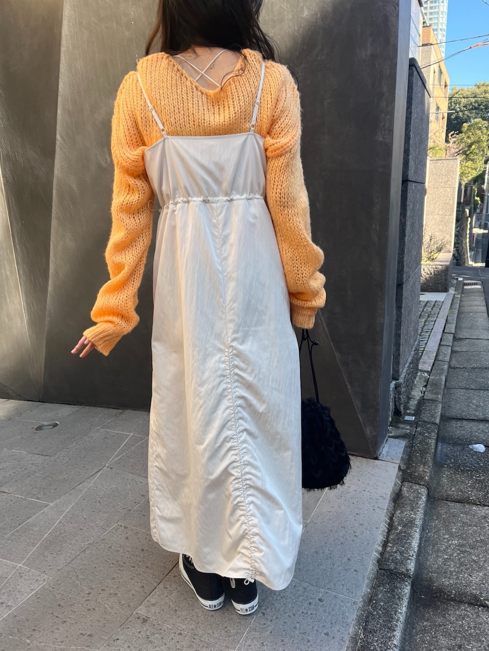 オレンジ系のニット/セーター、ホワイト系のワンピースを着用したレディースの春コーディネートの5枚目の写真