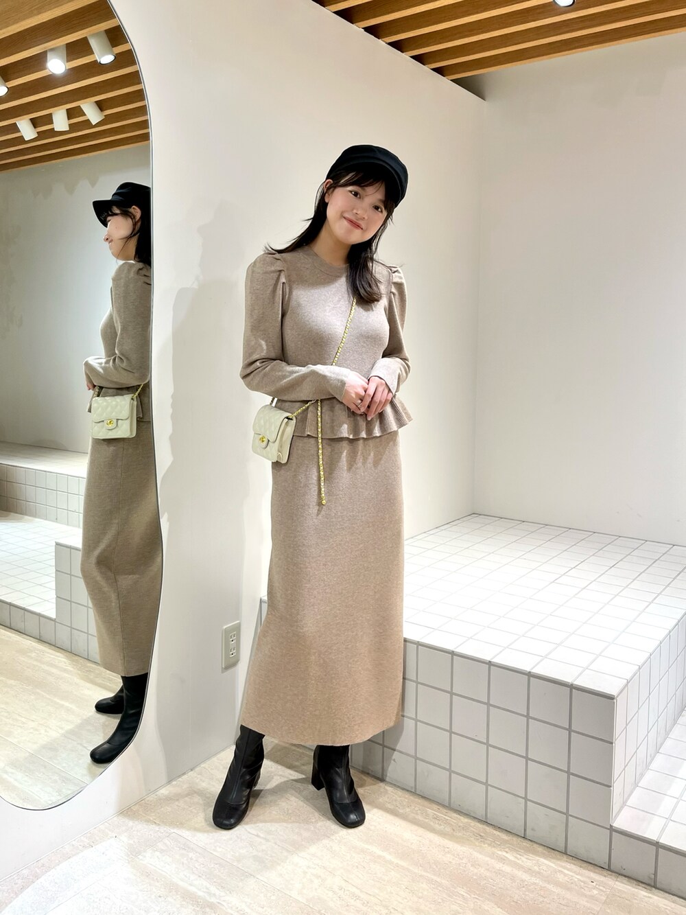 ベージュ系のワンピース、ホワイト系のショルダーバッグ、ブラック系のブーツを着用したレディースの冬コーディネートの3枚目の写真