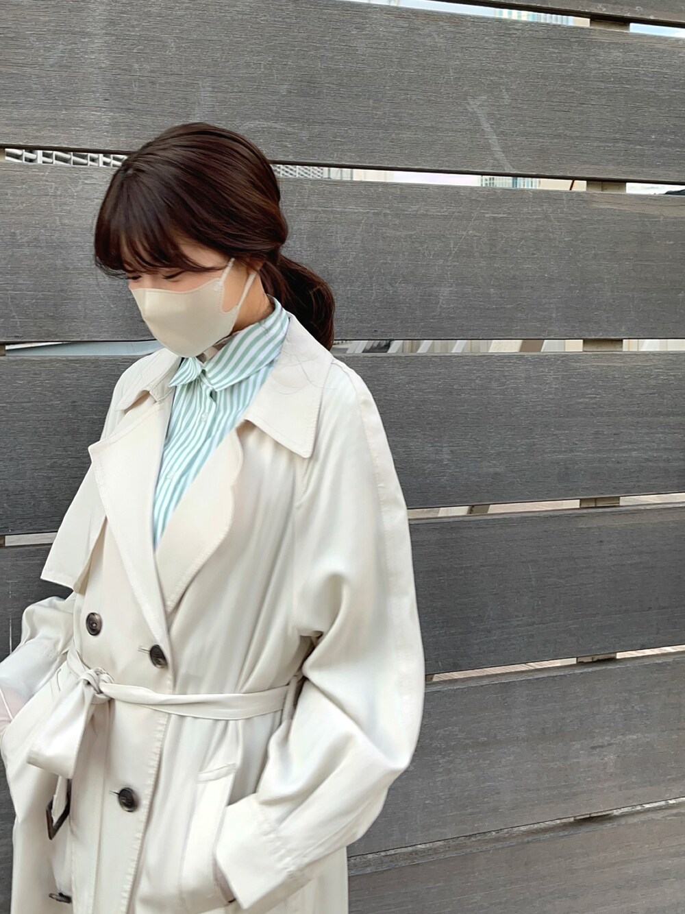 ベージュ系のトレンチコート、ブルー系のシャツ/ブラウスを着用したレディースの冬コーディネートの2枚目の写真