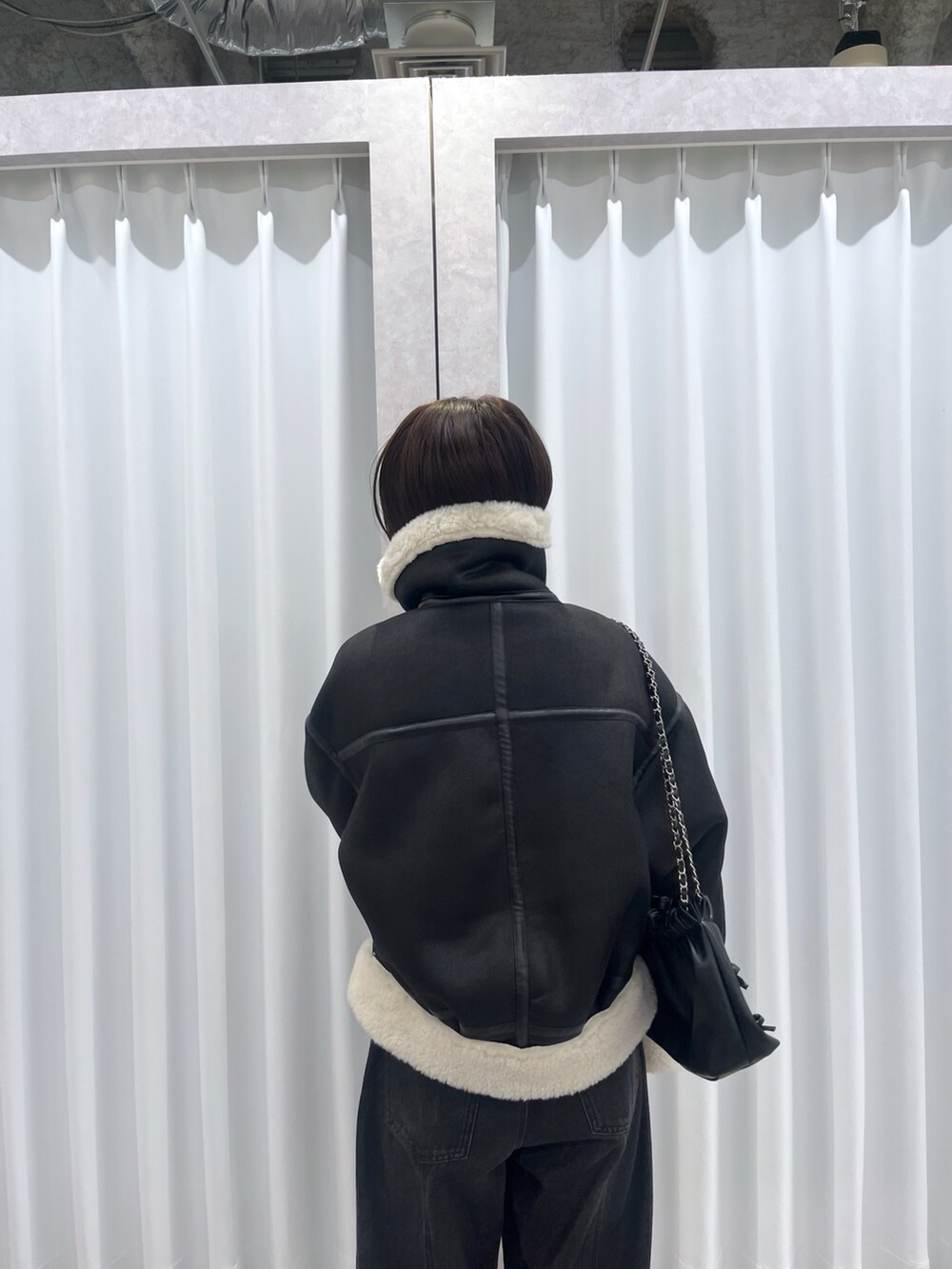 ブラック系のその他アウター、ブルー系のデニムパンツ、オレンジ系のニット/セーターを着用したレディースの冬コーディネートの7枚目の写真