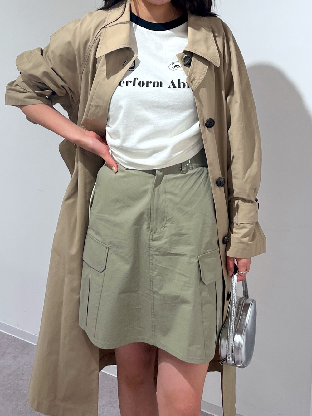 ベージュ系のトレンチコート、グリーン系のスカートを着用したレディースの春コーディネートの2枚目の写真