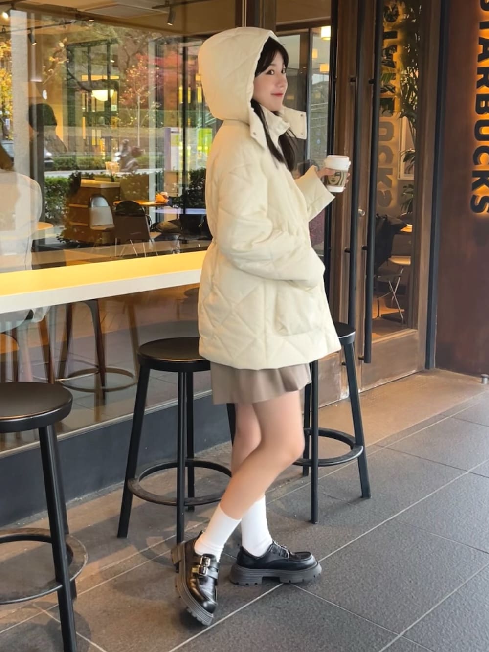 ホワイト系のダウンジャケット/コート、ブラック系のスカートを着用したレディースの冬コーディネートの2枚目の写真