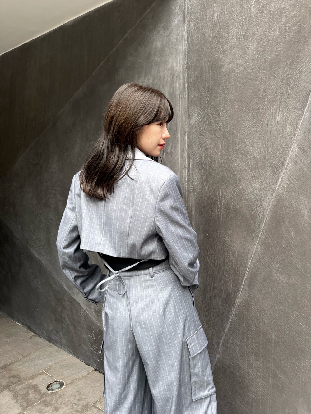 グレー系のテーラードジャケット、グレー系のスラックス、ホワイト系のスニーカーを着用したレディースの秋コーディネートの2枚目の写真