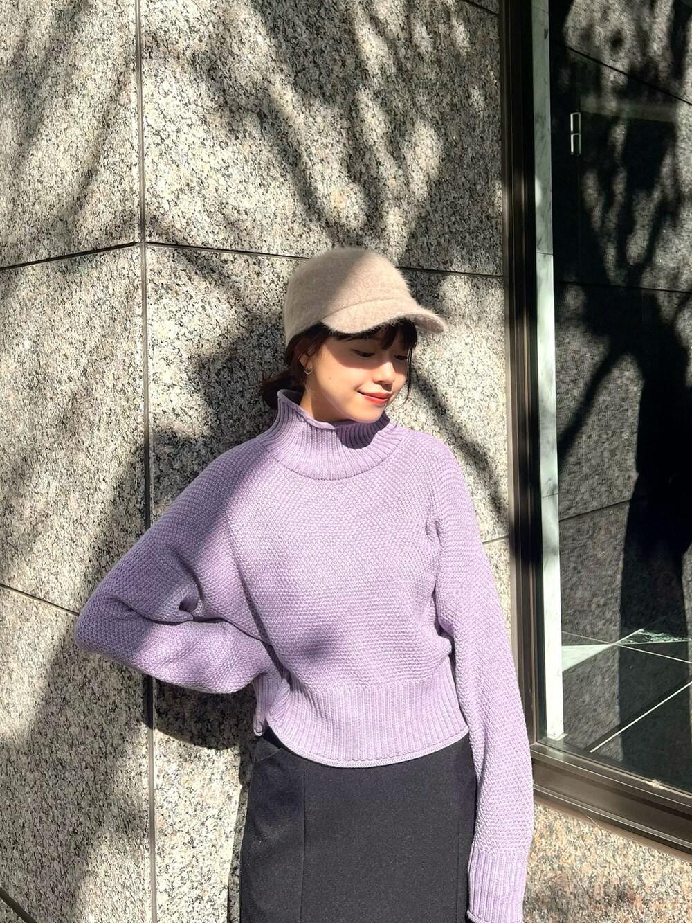 パープル系のニット/セーター、ブラック系のスカート、ホワイト系のブーツを着用したレディースの秋コーディネートの2枚目の写真