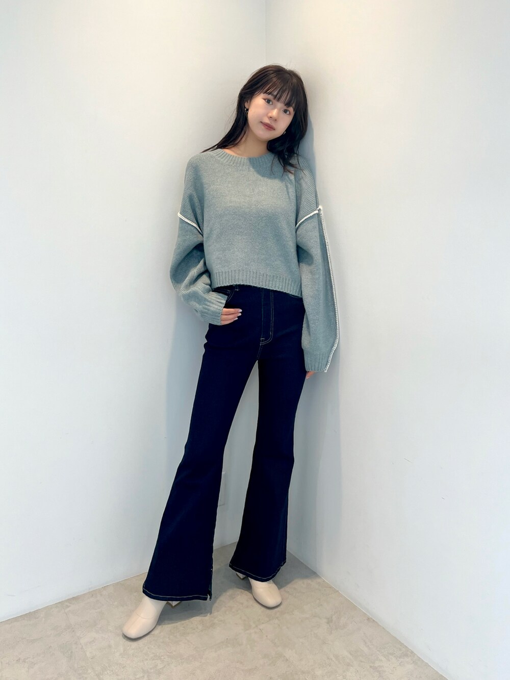 ブルー系のニット/セーター、ブルー系のデニムパンツ、ホワイト系のブーツを着用したレディースの秋コーディネートの2枚目の写真