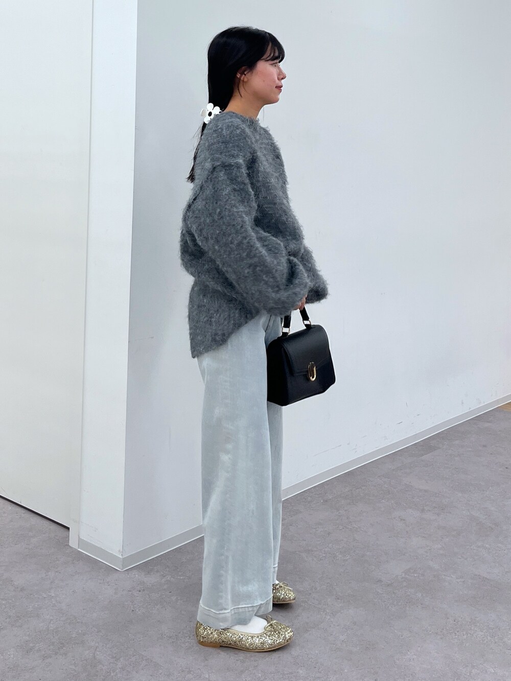 グレー系のニット/セーター、ブルー系のデニムパンツ、ブラック系のショルダーバッグを着用したレディースの冬コーディネートの2枚目の写真