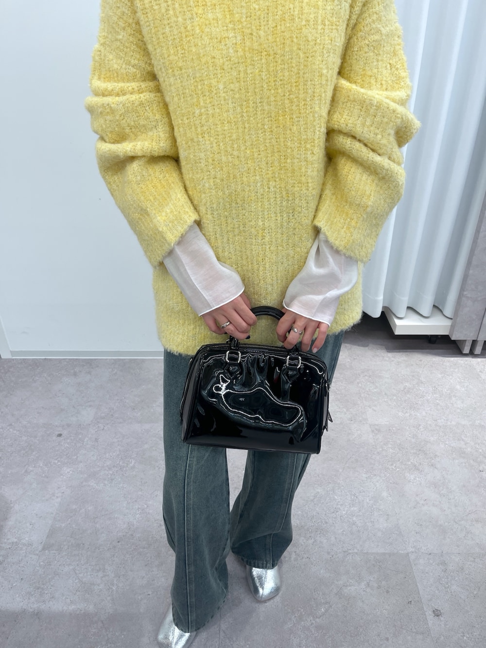 イエロー系のニット/セーター、ホワイト系のTシャツ/カットソー、ブルー系のデニムパンツを着用したレディースの冬コーディネートの3枚目の写真