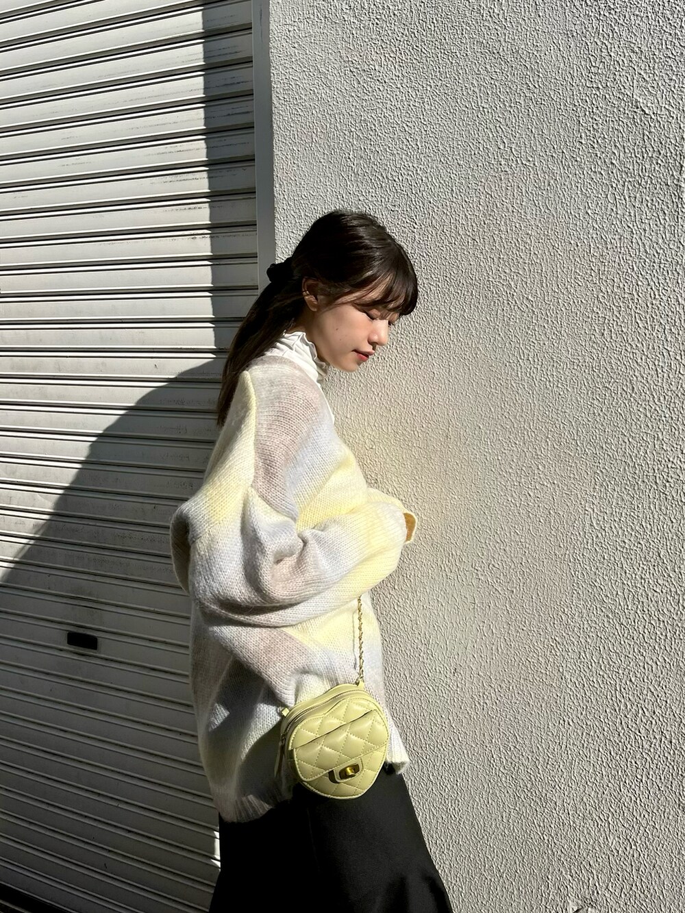 イエロー系のカーディガン/ボレロ、ブラック系のスカート、ベージュ系のブーツを着用したレディースの冬コーディネートの2枚目の写真