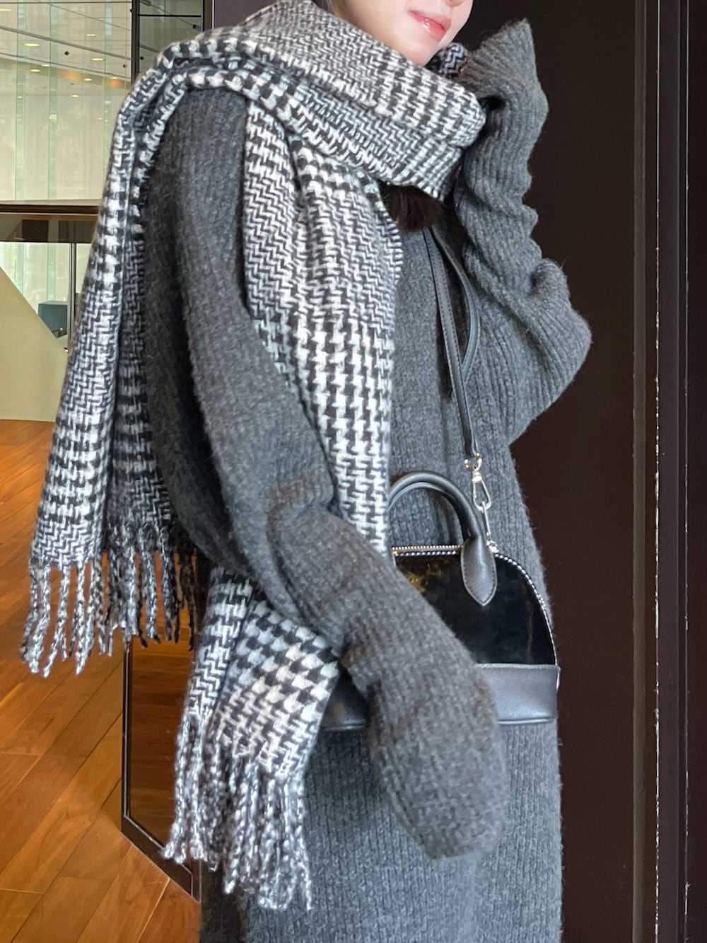 ブラック系のワンピース、オレンジ系のショルダーバッグ、ブラック系のマフラーを着用したレディースの冬コーディネートの3枚目の写真