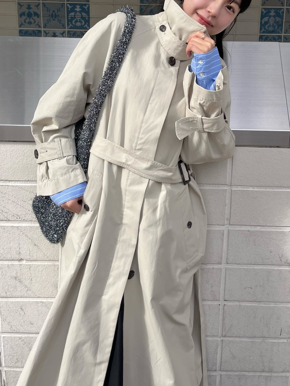 ベージュ系のトレンチコート、ホワイト系のスニーカーを着用したレディースの冬コーディネートの4枚目の写真