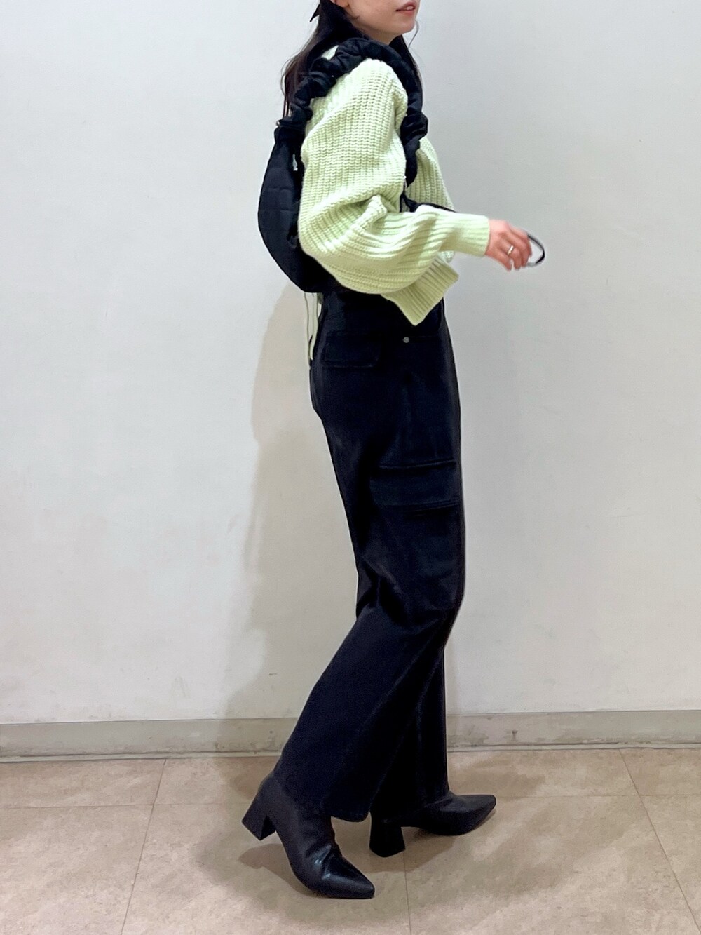 グリーン系のニット/セーター、ブラック系のデニムパンツ、ブラック系のキャップを着用したレディースの冬コーディネートの2枚目の写真