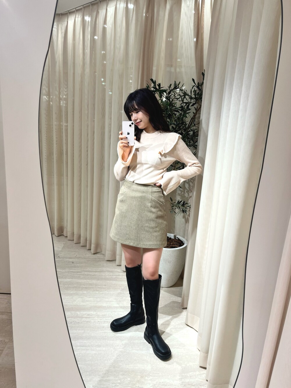 ベージュ系のニット/セーター、ブラウン系のスカート、ブラック系のブーツを着用したレディースの冬コーディネートの2枚目の写真